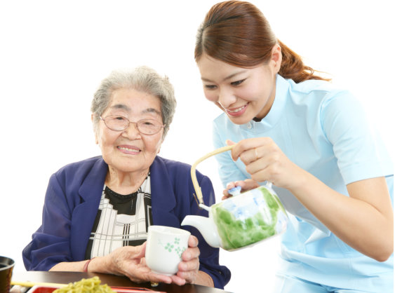 Friendly nurse cares for an elderly woman eating soba